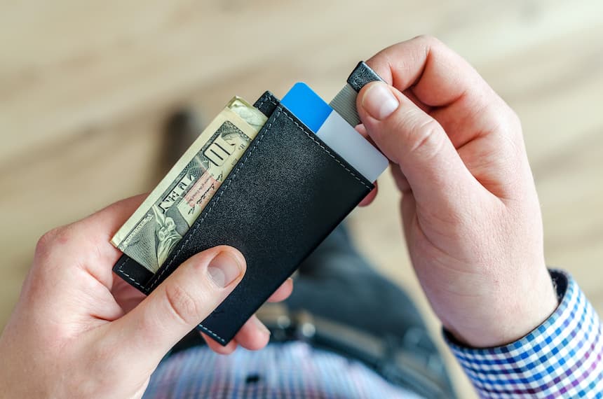 hands reaching on a tab of a wallet to pull out credit card