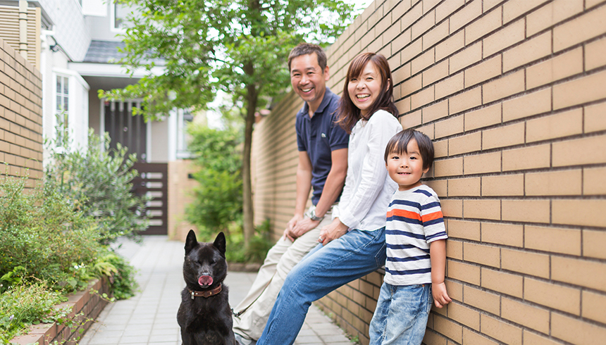 asian family of three and their dog outside their home