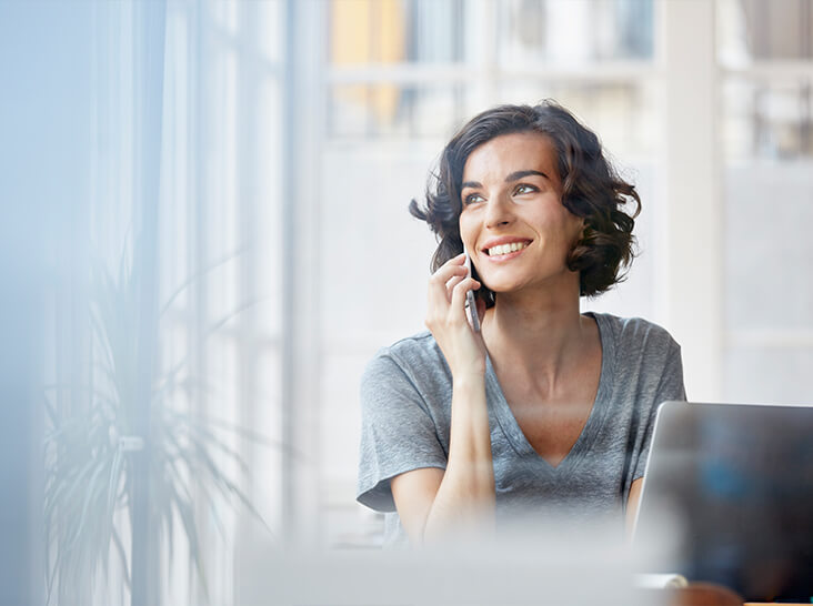 A woman sits at her desk and uses her mobile phone.