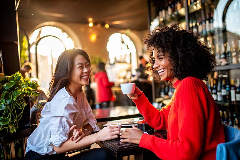 Two women in a restaurant smile and laugh.