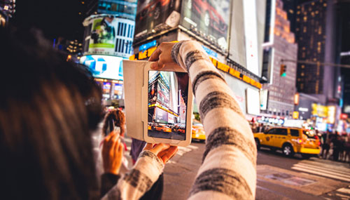 Young woman capturing images in Times Square with a tablet