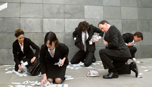 Business people filling pockets and bag with fallen money