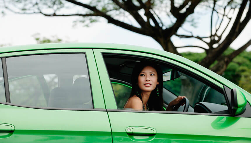 坐在绿色汽车中的女生，正望向窗外 