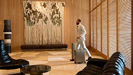 Man with two suitcases walking through the lobby of Hollywood Proper Residences
