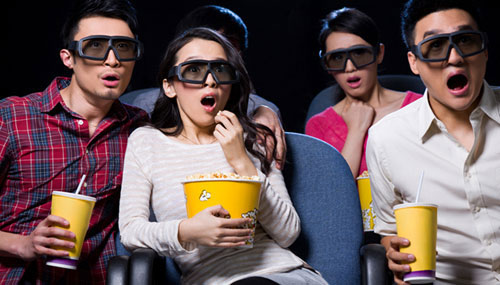 Young people watching a 3D movie in movie theatre 