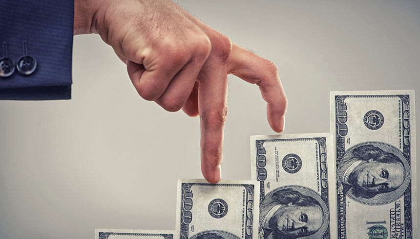 Close up concept shot of fingers walking crawling up a pile of one hundred dollar, deciding how to fund your busienss