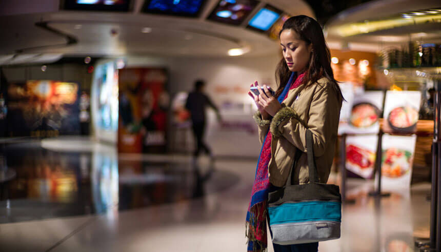 Young woman using a smartphone while waiting to get into the cinema for a movie