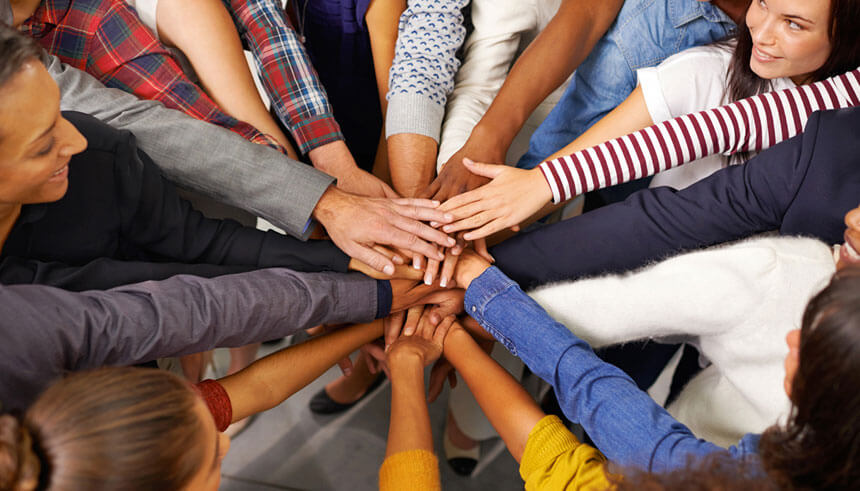 Shot of a diverse group of employees joining their hands in a symbol of unity