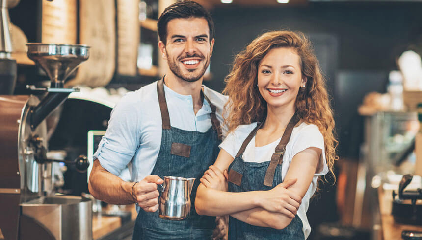 Two small business owners smiling, knowing confidently that their business is insured by business insurance