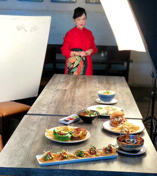 Chef Theresa Lin standing next to a table with dishes from Tru Grits