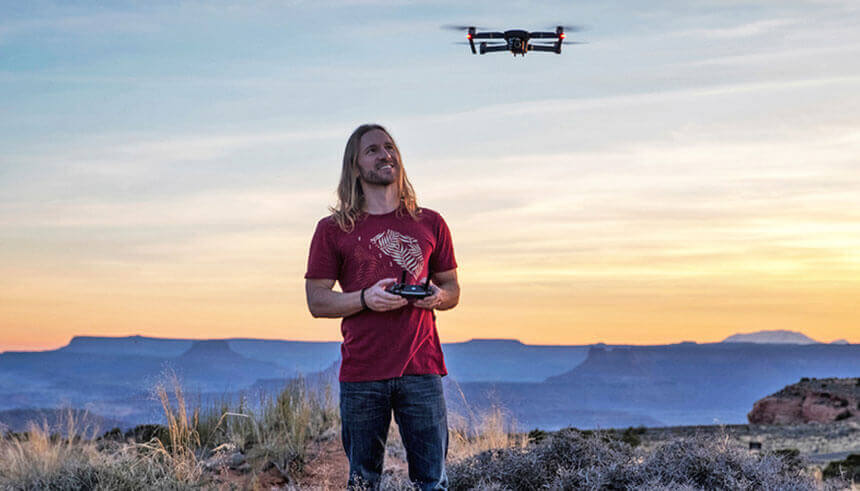 Man operating a drone while stanging on a cliff in Grand Canyon