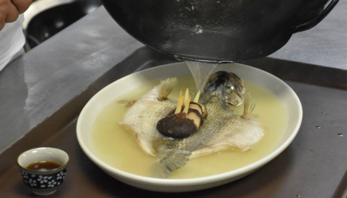 Pouring out the wine broth on steamed bass