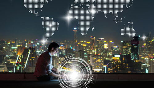 Asian businessman sitting and using the laptop with Network graphic over the world map dot and cityscape background at night time