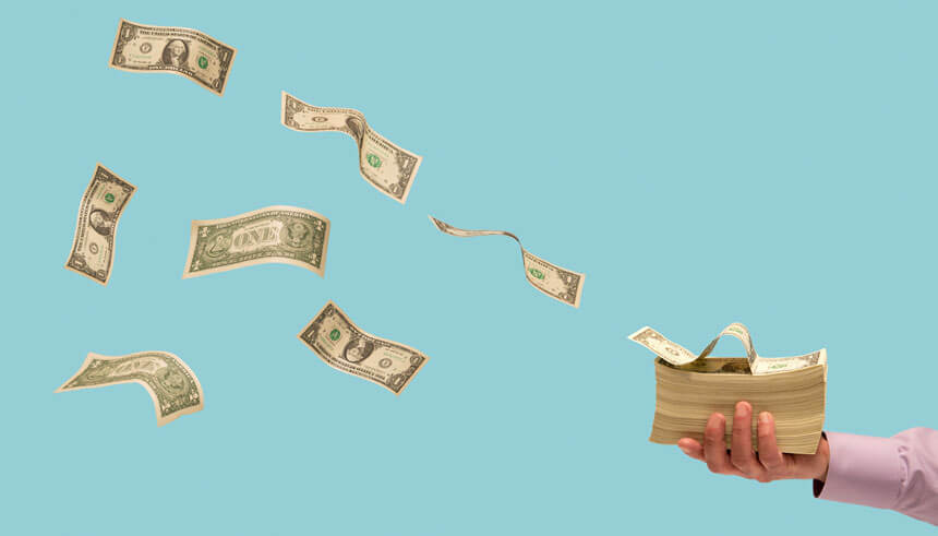 Money flying off stack of bills in man's hand, representing cash flow management 