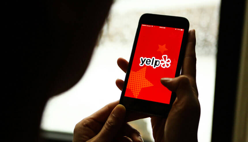 A person is about to look at Yelp app on their phone for business reviews