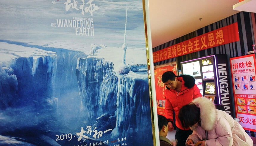 People standing next to a poster of 'The Wandering Earth' in China