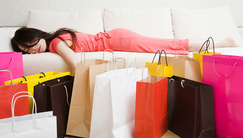 一位千禧一代女性在一天的购物后，疲惫的睡在沙发上