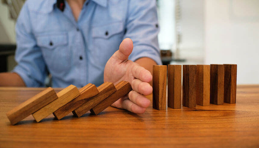 Business man playing with dominoes, thinking how to protect his business against supply chain disruption 