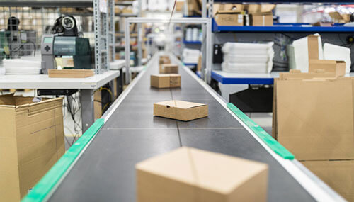 Cajas de cartón en cinta transportadora en un almacén de distribución de Amazon